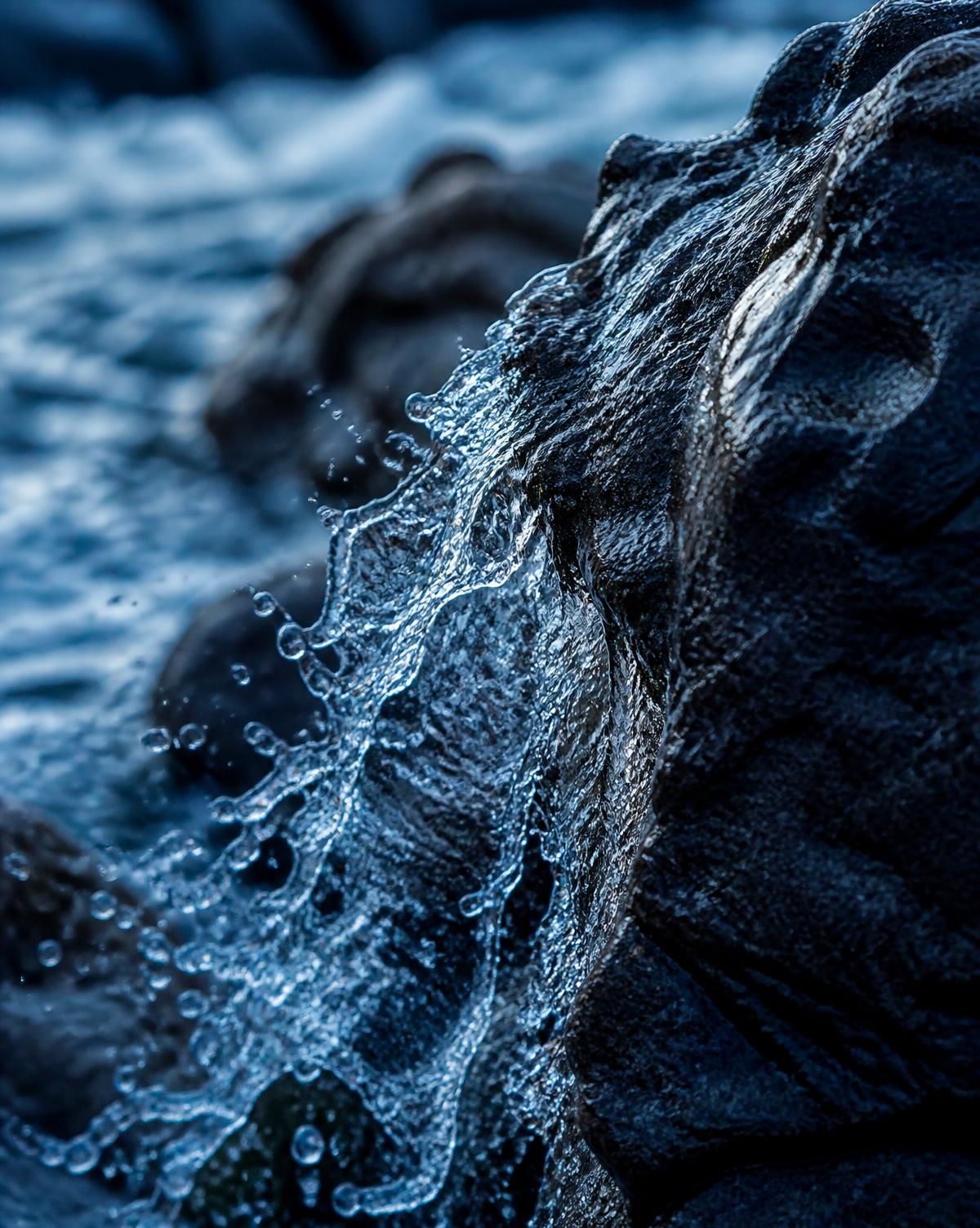 Pristine spring water flowing over dark volcanic stone